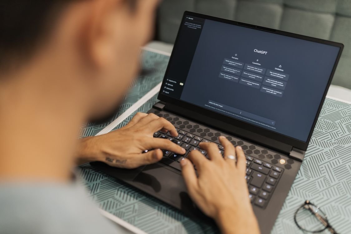 Person typing on a laptop displaying the ChatGPT interface, representing the new visual ads format in ChatGPT