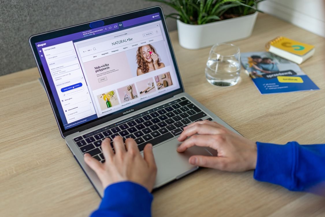 Person typing on a laptop displaying an e-commerce website, illustrating Google Ads scanning websites for promotions