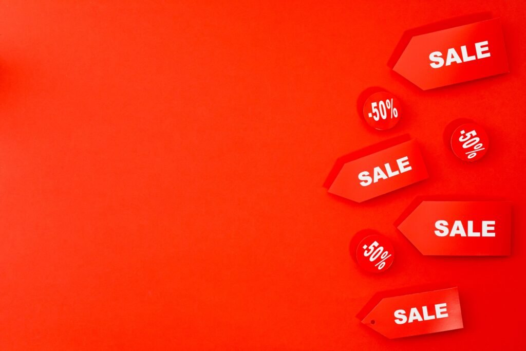 Red sale tags and discount labels on a red background, illustrating the promotions Google Ads pulls into ad assets